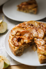 pie with caramelized apples in section, a piece of cake on a white plate, apple slices