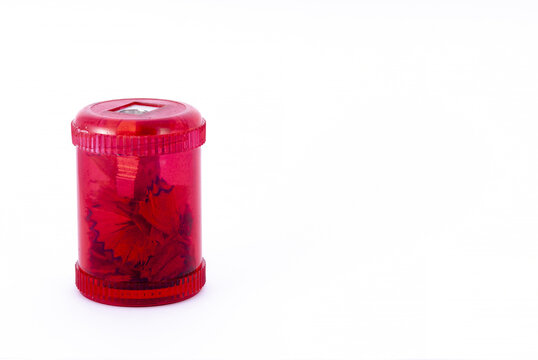 Closeup shot of a red pencil sharpener with shavings isolated on a white background