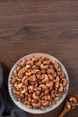 Cashew nuts with peel in a plate on wooden tray.