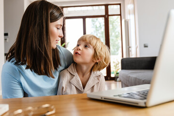 Woman at home with her son using laptop computer