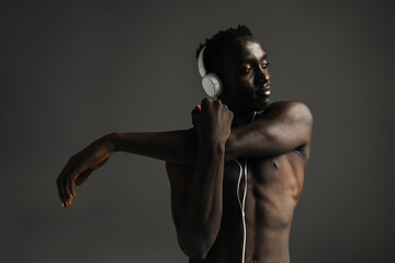 African american sportsman using headphones while stretching his arm