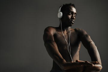 Obraz premium African american sportsman using headphones while stretching his hands