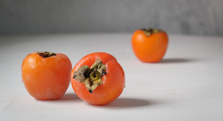 Ripe orange persimmons on the light background.