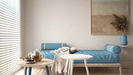 Cosy wooden sustainable living room in blue tones with modern sofa with blanket and coffee tables. Tea time, glass teapot and teacup, snacks. Environmental friendly interior design