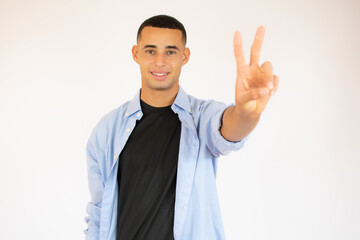 Young man with a gesture of victory over white background.