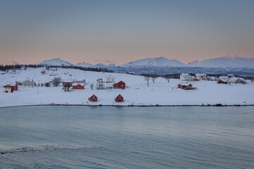 Small town with red cabins among the snow and mountains