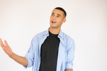 Photo of amazed man in basic clothing screaming in surprise or delight and raising arms isolated over white background