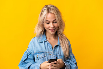 Young Russian woman isolated on yellow background sending a message with the mobile