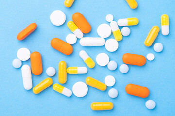 Multicolor tablets and pills capsules on blue background Close-up Top view