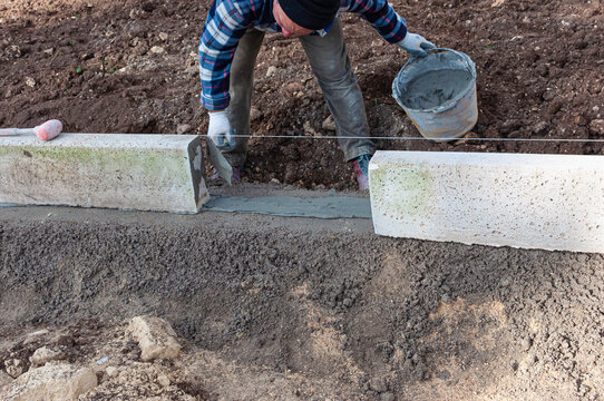 Construction site, worker installing curb stone