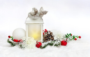 Christmas decoration. Christmas lantern, white openwork flowers poinsettia, white balls, cones, red apples, berries, twigs christmas tree on snow, covered snow on light background with space for text