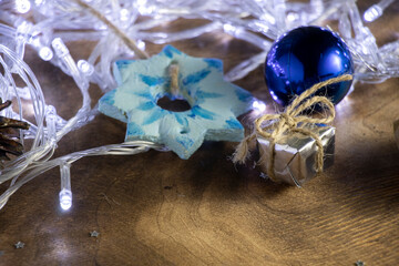 A Christmas gift in silver paper and a Christmas tree toy - a blue ball on a background of white lights.