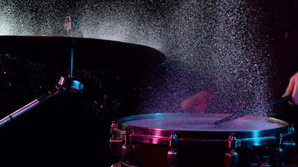 Freeze motion of drummer hitting drums with water splashes