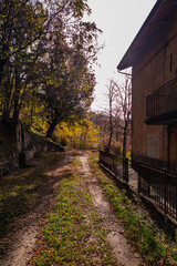 autunno in montagna, vecchia fonte alberi e scorcio cielo, sentiero davanti ad un casolare