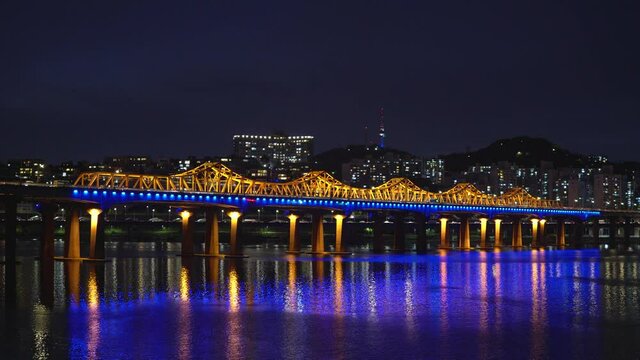 Illuminated Dongho Bridge With High-rise Buildings And Namsan tower In Background spanning over Han River At Night In Seoul, South Korea. - wide static shot
