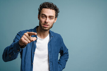 Displeased handsome guy looking and pointing finger at camera