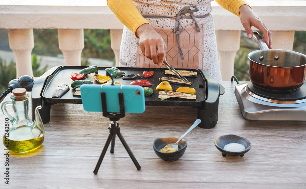 Wall mural young woman chef cooking outdoor while streaming online with phone for webinar class lesson at home 