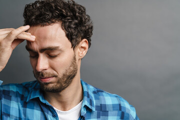 Unshaven handsome guy with headache posing on camera