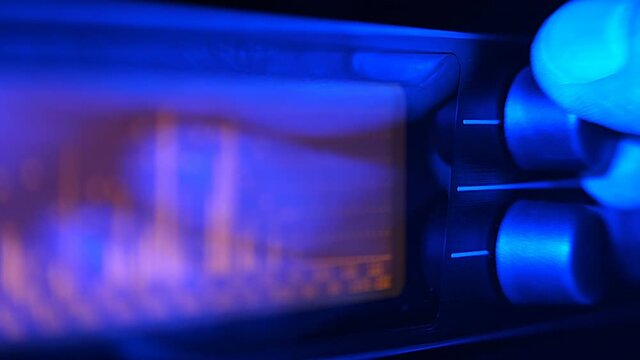 The hand turns the controls on the front panel of the equalizer and adjusts the volume level, the dynamics of the music, the priority of the selected frequencies in the range. Closeup
