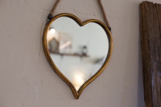 A Heart-shaped Mirror With Wooden Frame Hanging On White Wall.
