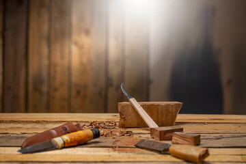 Craftsman carving tools with a chisel  carving knife a piece of dark wood on carpentry workbench 