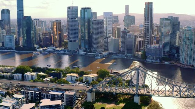 Vehicles Travelling Across Story Bridge Over Brisbane River At Sunset With High Rise Buildings At Brisbane CBD, Queensland, Australia. - aerial sideways