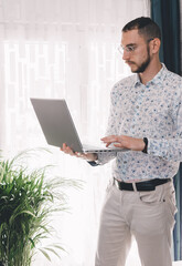 Young man making a call using a smartphone and laptop for work. Concept working home during 2020 covid coronavirus pandemic