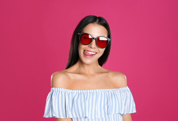 Beautiful woman wearing sunglasses on pink background