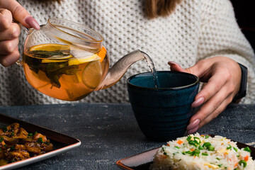 a woman pours tea into a Cup