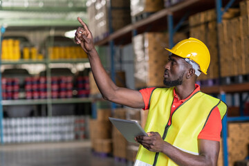 Africa American workers using tablets and checks goods in the automotive parts warehouse...