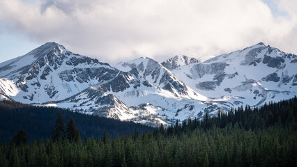 Iconic Canadian alpine landscape - snow-capped mountains and coniferous forest  on an early morning.