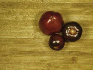 Kumato tomatoes on the rustic wooden background. 'Kumato' is a cultivar of dark tomato yet known as 'Olmeca'