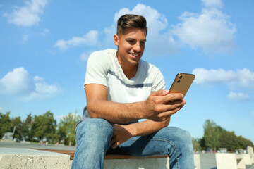 Handsome man using modern mobile phone outdoors, focus on hand