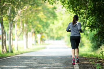 Fototapeta premium Healthy woman jogging run and workout on road outdoor. Asian runner people exercise gym with fitness session, nature park background.