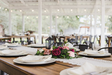 Decorated Wooden Wedding Reception Farm Table in a White Barn Outside with Natural Light and Market Lights in Background