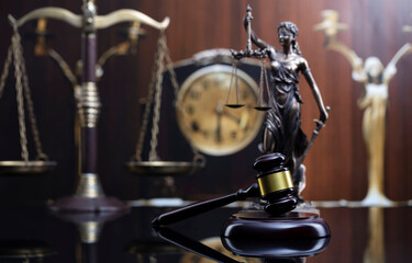 Fototapeta na wymiar Law concept. Judge wooden gavel, scale, old clock and Themis statue on brown background.