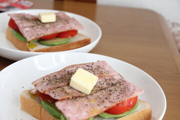 パンとバターとトマトとアボカドをのせた白いお皿