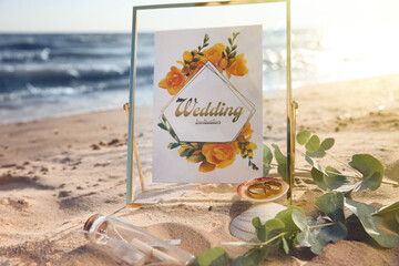 Composition with gold wedding rings on sandy beach