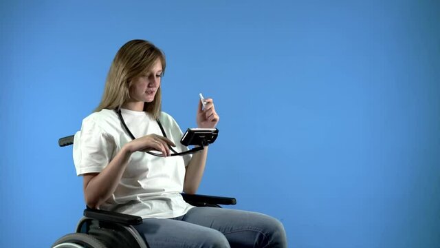 a disabled girl in a wheelchair smokes an electronic cigarette and looks at the phone
