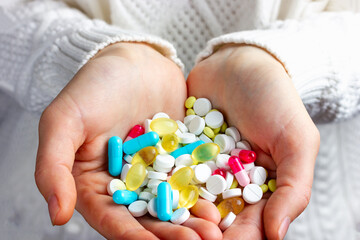 Many multi-colored medical tablets, pharmaceutical pills lie in the hands. Hands with medicine, multi-colored pills.