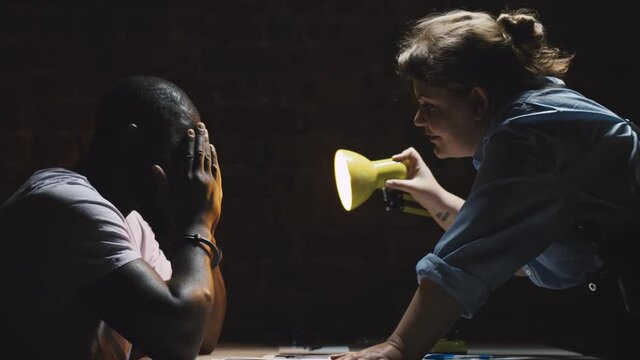 Side view of woman police officer psychologically abusing suspect man while interrogating