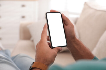 Man holding mobile phone with empty screen indoors, closeup