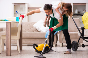 Fototapeta na wymiar Young male contractor cleaning the house with his small daughter