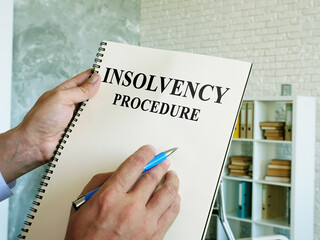 The man reads the insolvency procedure in the book.