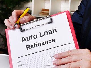 Auto loan refinance concept. The man offers to sign the document.