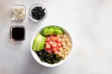 buddha bowl with quinoa, salmon, wakame seaweed, avocado and cucumber. Diet food. Top view. place for text. grey background