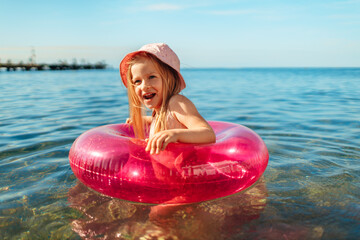 Girl kid in pink panama swimming in sea with circle