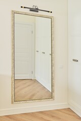 Large interior mirror in vintage white bronze wooden frame on wall