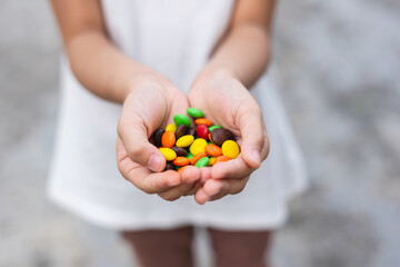 Child hands with candies, colorful chocolate peanut.