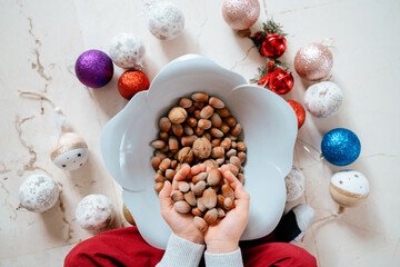 Fototapeta na wymiar Horizontal view of unrecognizable little kid hands full with december season hazelnuts. Christmas and seasonal food and ornaments background concept.